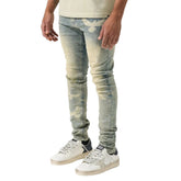 Person wearing light blue distressed jeans and white sneakers on a white background