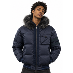 A man wearing a navy blue puffer jacket with a dark gray faux-fur trimmed hood and ribbed knit collar, shown against a plain white background.